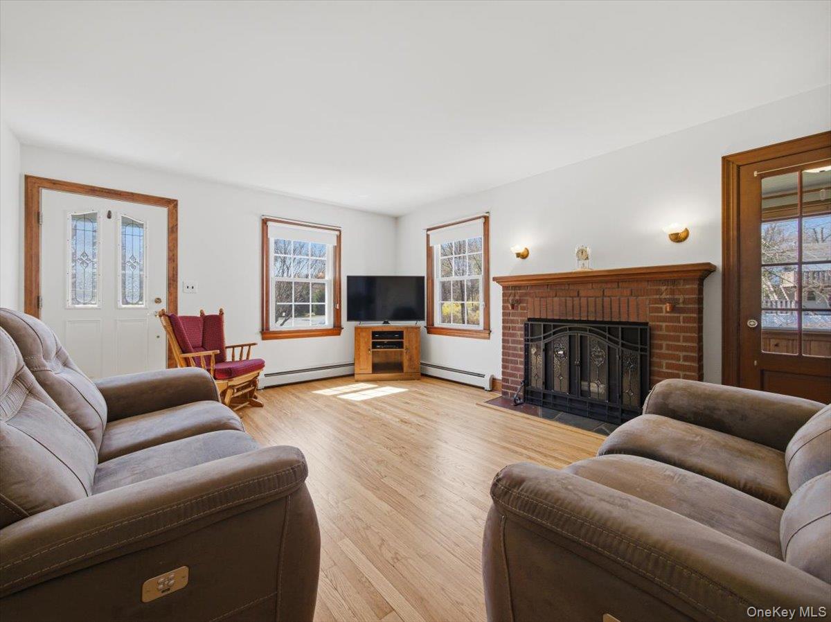 311 Gate Hill Coop Road Stony Point, NY 10980 - Photo 6 of 42 This living area features light wood flooring, white walls, and a brick fireplace with a black iron grate