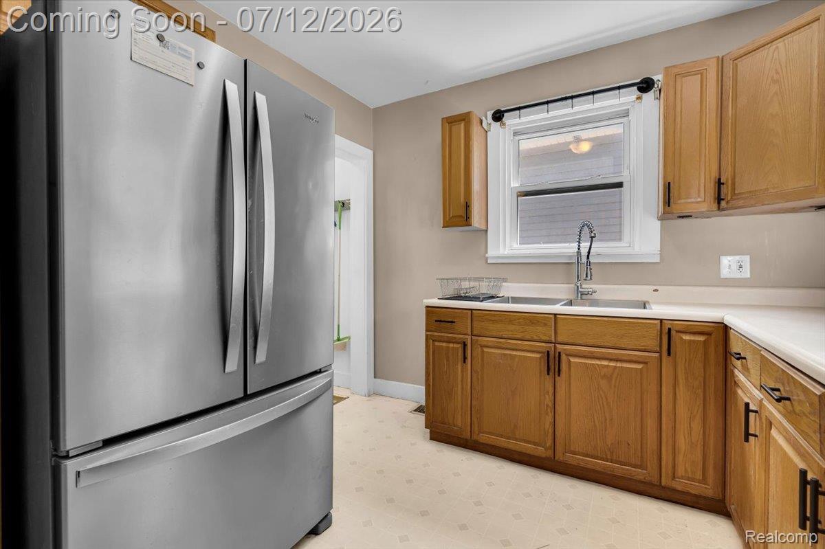 624 North Prospect Road Ypsilanti, MI 48198 - Photo 16 of 28 Kitchen featuring wood cabinetry with dark hardware, a double basin stainless steel sink with a gooseneck faucet, light-toned countertops, and patterned flooring