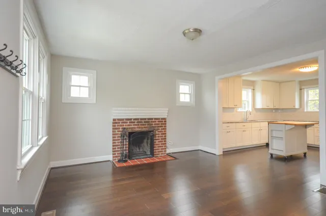 an empty room with wooden floor a fireplace and windows