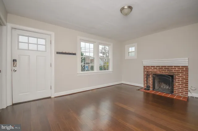 an empty room with wooden floor fireplace and windows