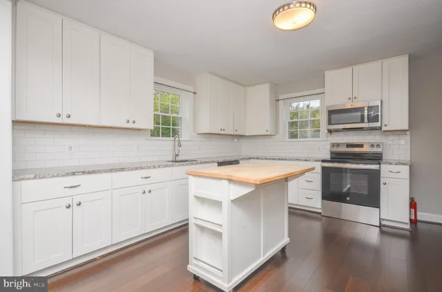 a kitchen with a refrigerator a sink and dishwasher with wooden floor