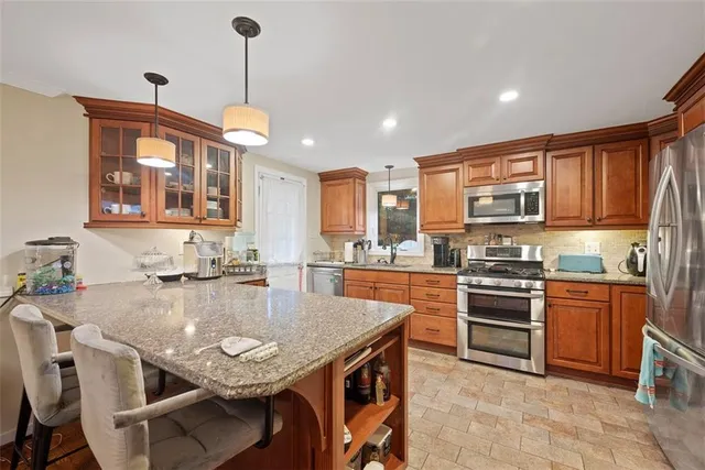 a kitchen with kitchen island granite countertop a stove a sink a dining table and chairs