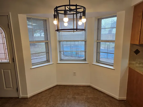 an empty room with windows wooden table and front door