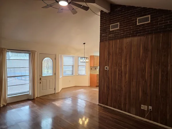 an empty room with wooden floor cabinet and windows