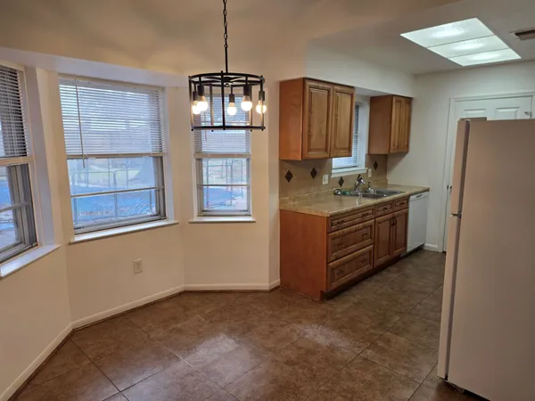 a kitchen with stainless steel appliances granite countertop a refrigerator a sink dishwasher a stove a dining table and chairs with wooden floor