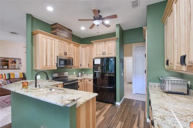 a kitchen with stainless steel appliances kitchen island granite countertop a sink stove and refrigerator