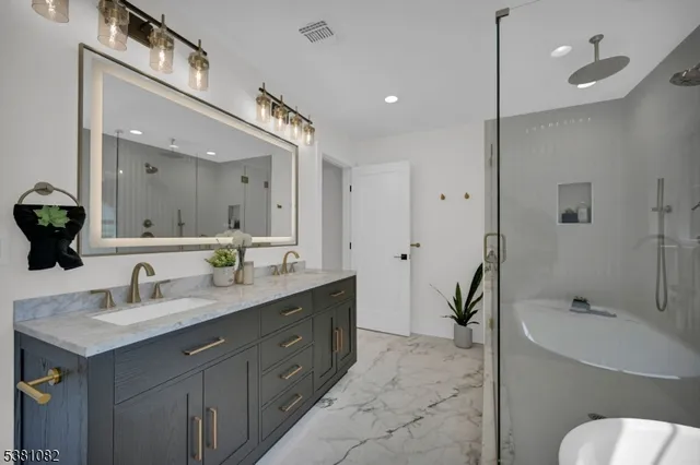 a spacious bathroom with a granite countertop sink mirror and bathtub