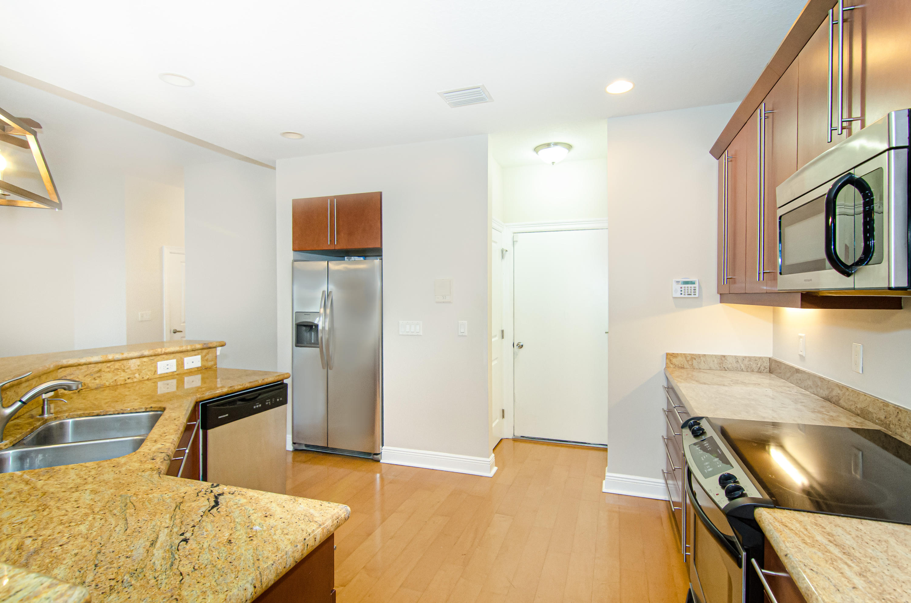 816 Prosperity Farms Road, Unit 2 North Palm Beach, FL 33408 - Photo 6 of 30 a kitchen with stainless steel appliances kitchen island a stove a refrigerator with white cabinets and wooden floor