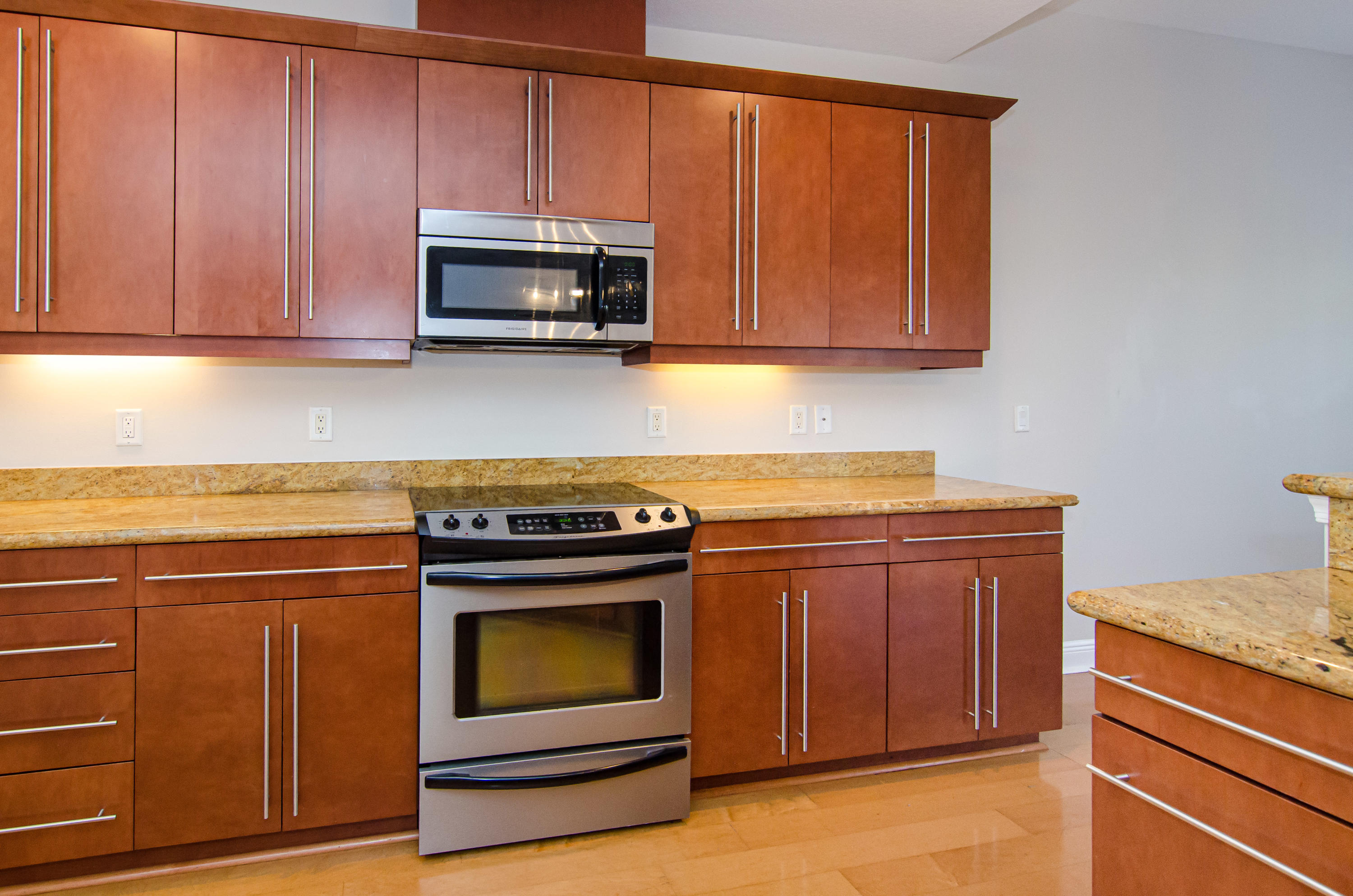 816 Prosperity Farms Road, Unit 2 North Palm Beach, FL 33408 - Photo 10 of 30 a kitchen with granite countertop a stove top oven microwave and cabinets