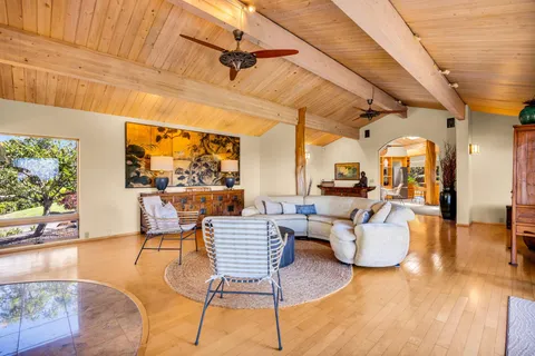 a living room with couches and a dining table with wooden floor