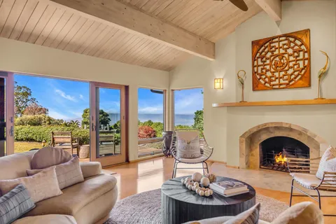 a living room with furniture a fireplace and a floor to ceiling window