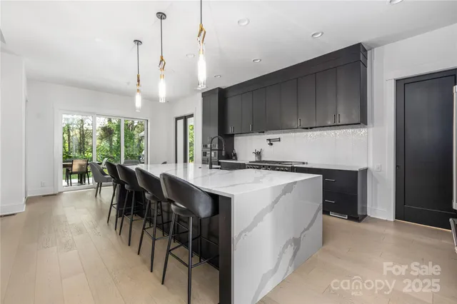 a kitchen with kitchen island granite countertop a stove a refrigerator a sink a dining table and chairs with wooden floor