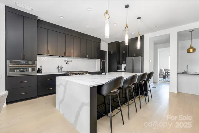 a kitchen with stainless steel appliances kitchen island granite countertop a sink a stove and a refrigerator