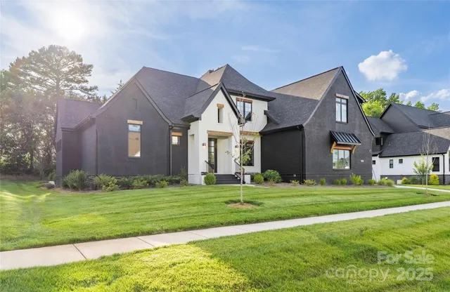 a front view of a house with a big yard and a large tree