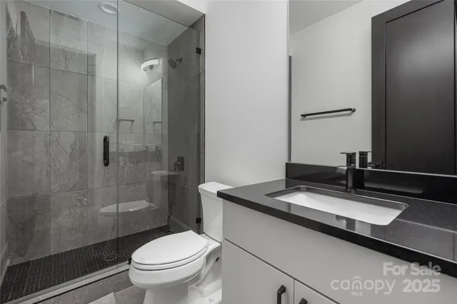 a bathroom with a granite countertop sink a toilet a mirror and shower