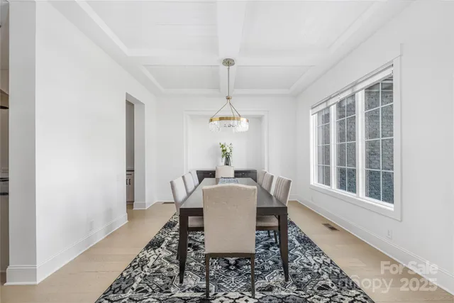 a dining room with wooden floor a chandelier and windows