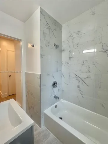a bathroom with a tub shower and sink