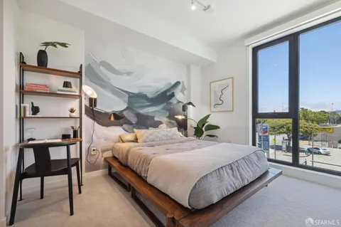 a bedroom with a bed a table and large window