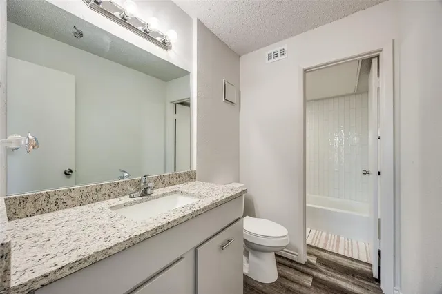 a bathroom with a granite countertop sink toilet and shower