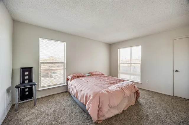 a bed sitting in a spacious bedroom next to a window and closet