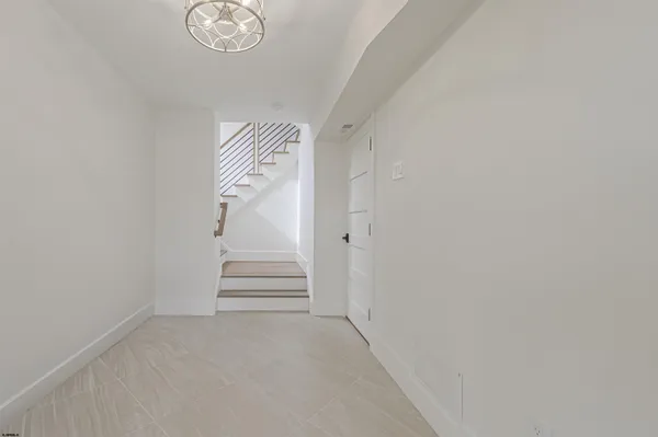 a view of an empty room with wooden floor and a kitchen