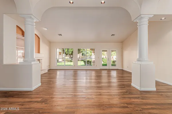 a view of an empty room with wooden floor and a window