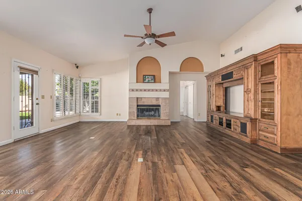 a view of an empty room with wooden floor and a window