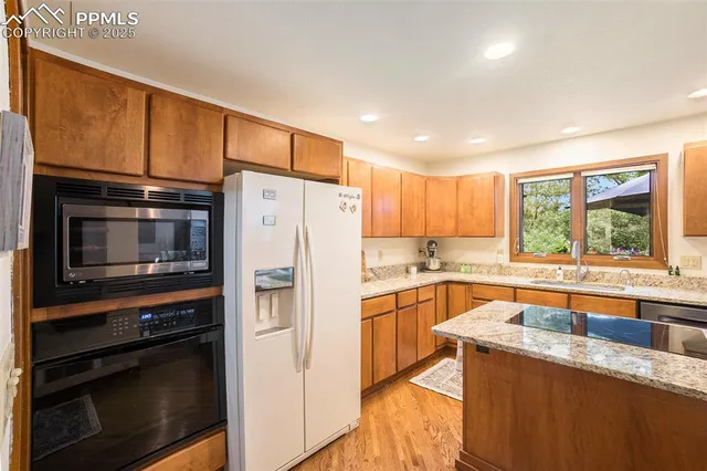 a kitchen with granite countertop a refrigerator stove and sink