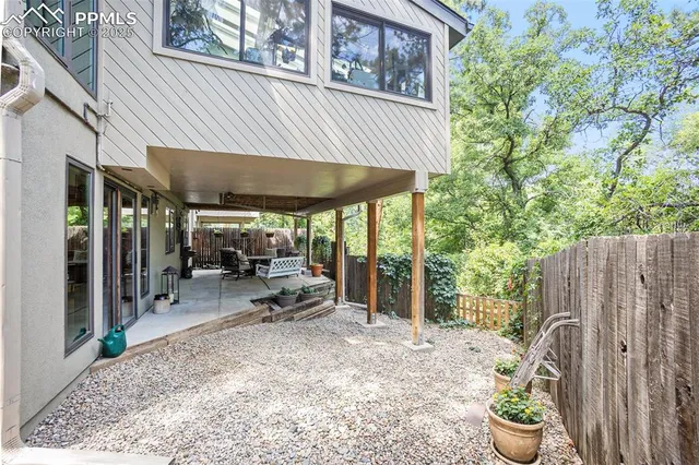 a view of a patio with table and chairs under an umbrella with a small yard