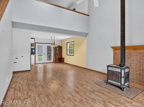56375 Bates Road New Baltimore, MI 48051 - Photo 13 of 35 Vaulted ceiling with a ceiling fan, wood-finish flooring, wood-burning stove with a tiled hearth and surround, and double glass doors