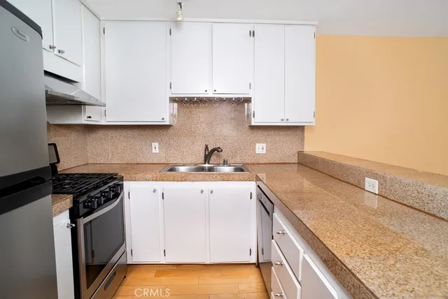 a kitchen with granite countertop a sink a stove and cabinets