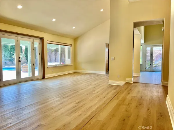 a view of an empty room with glass door and wooden floor