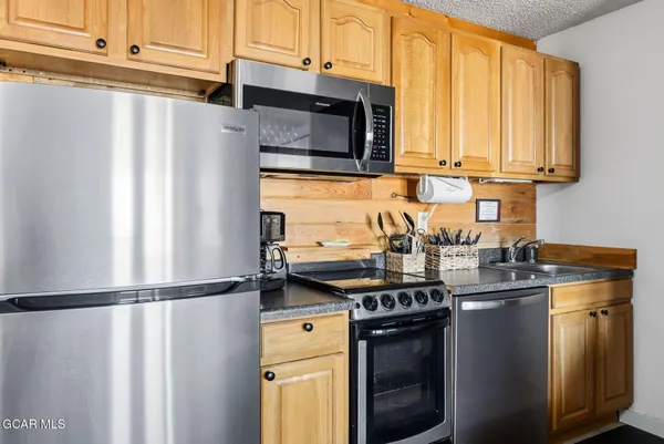 a kitchen with stainless steel appliances granite countertop a refrigerator stove a sink and dishwasher with wooden floor