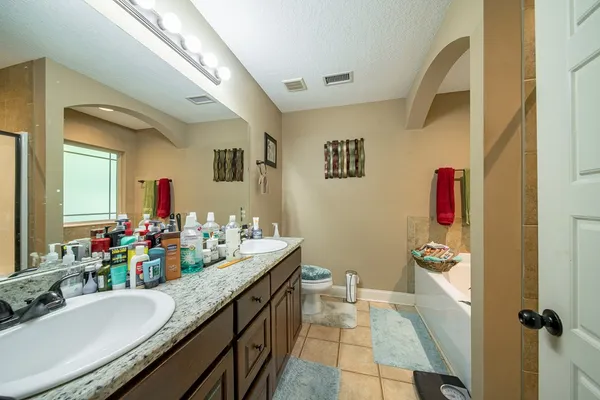 a bathroom with a granite countertop double vanity sink a mirror and a shower