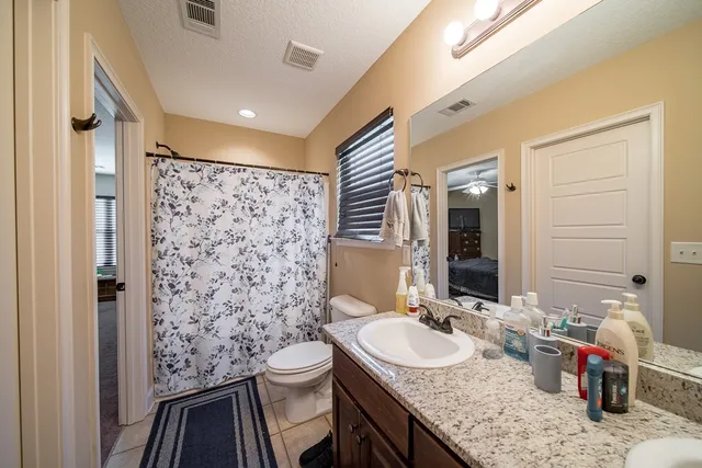 a bathroom with a granite countertop sink a mirror a toilet and shower
