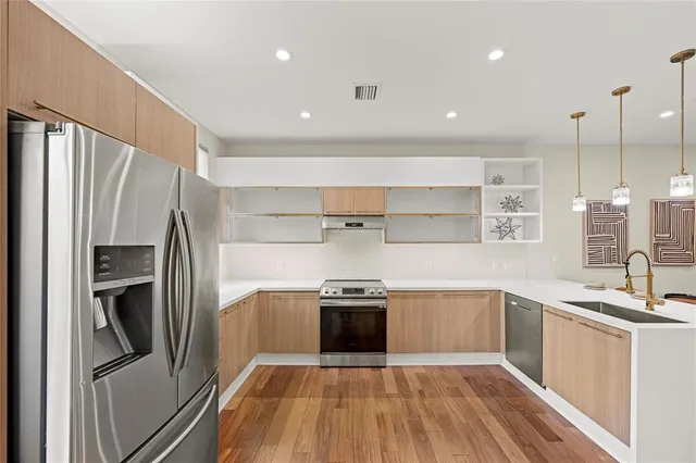 a kitchen with stainless steel appliances granite countertop a refrigerator a sink and a stove