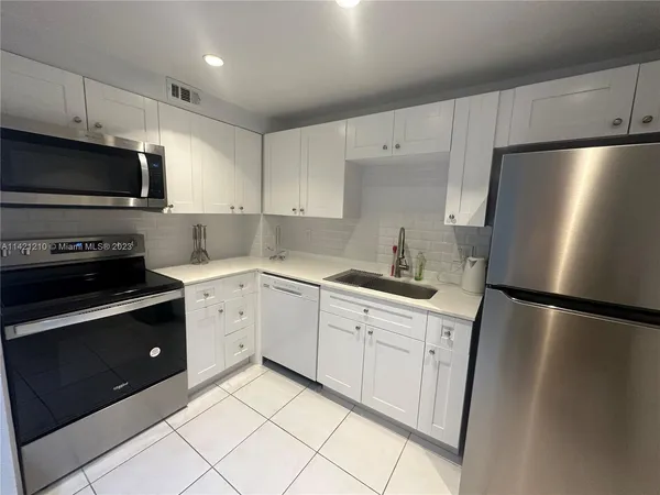 a kitchen with a refrigerator sink and white cabinets