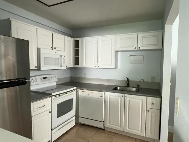 a kitchen with granite countertop white cabinets and white appliances