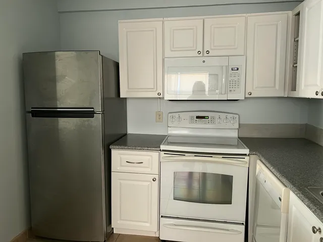 a kitchen with white cabinets and white appliances