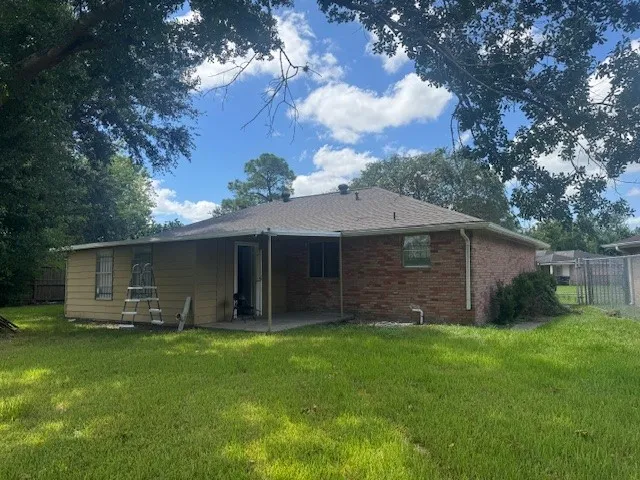 a view of a house with a yard and a large tree