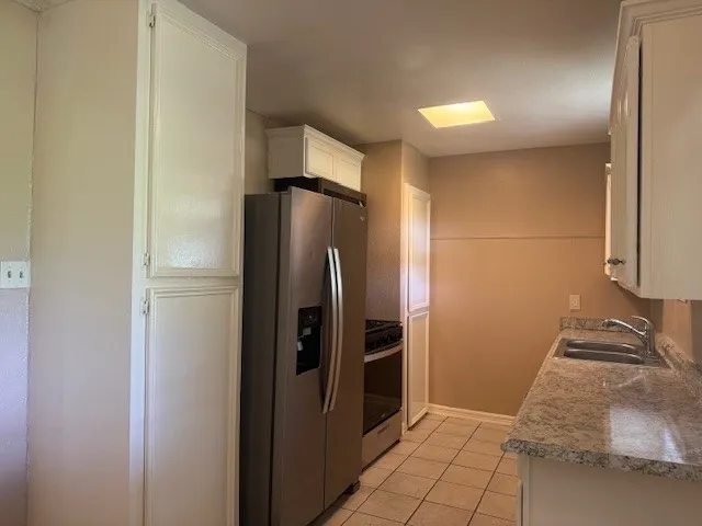 a view of a refrigerator in kitchen and an empty room