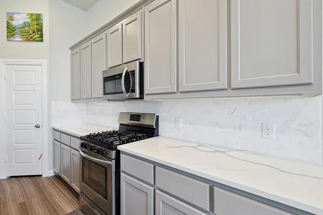 a kitchen with granite countertop white cabinets stainless steel appliances and wooden floor