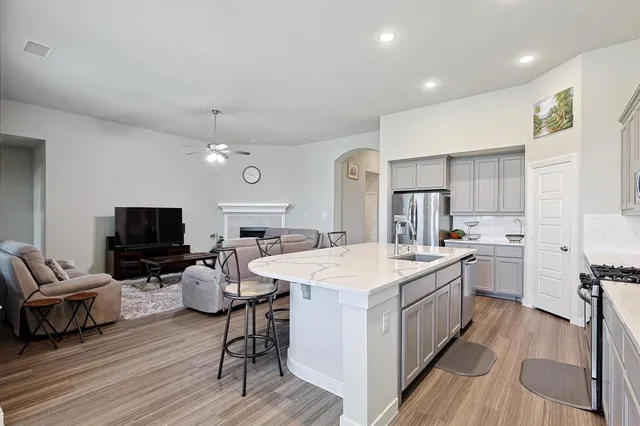 a large kitchen with sink a microwave oven a stove and white cabinets with wooden floor