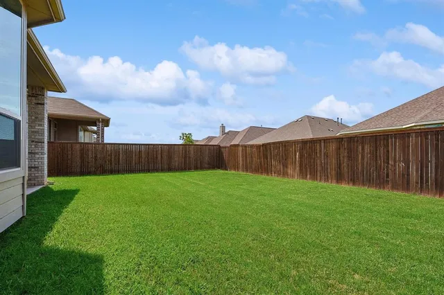 a view of a backyard with grass and wooden fence