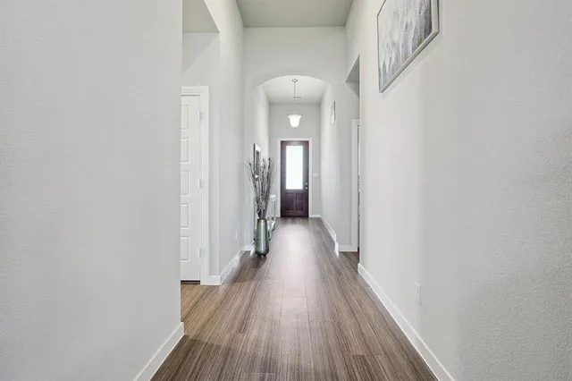 a view of a hallway with wooden floor and a bathroom