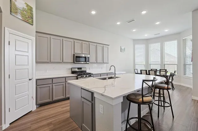 a kitchen with a sink stove and white cabinets with wooden floor
