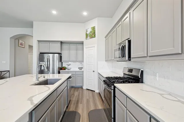 a kitchen that has a lot of cabinets a sink and appliances