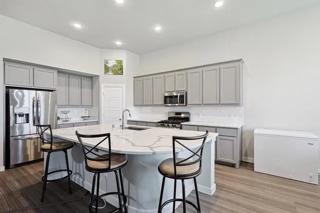 a kitchen with stainless steel appliances a table chairs refrigerator and microwave