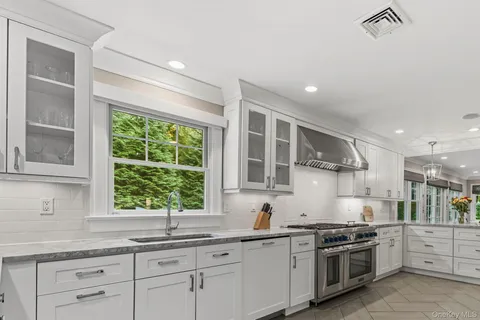 a kitchen with stainless steel appliances granite countertop white cabinets and a window