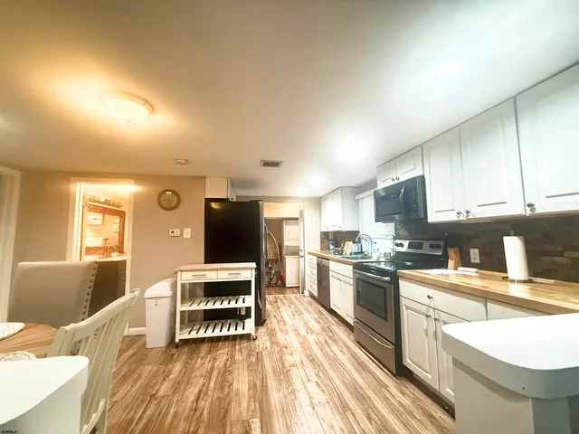 a kitchen with stainless steel appliances a stove top oven a sink a dining table and chairs